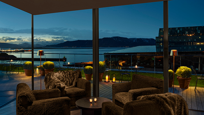 A common area inside The Reykjavik EDITION. Floor-to-ceiling windows next to plush chairs allow guests to admire the picturesque landscape in absolute comfort.
