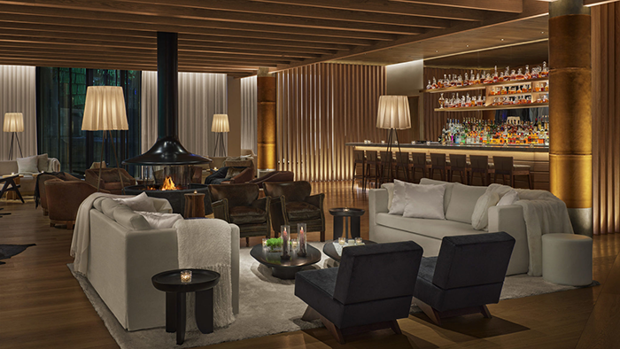 A bar and lounge area inside The Reykjavik EDITION. The bar seems to have a large whiskey selection on its top shelf.
