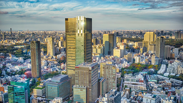 An exterior view of the The Ritz-Carlton, Tokyo. The hotel stands tall above the neighboring buildings, with the tokyo cityscape stretching to the horizon in the background.