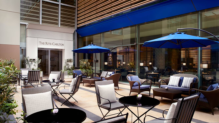 A quaint outdoor seating area at The Ritz-Carlton, Tokyo. Blue umbrellas provide shade during the sunny hours.