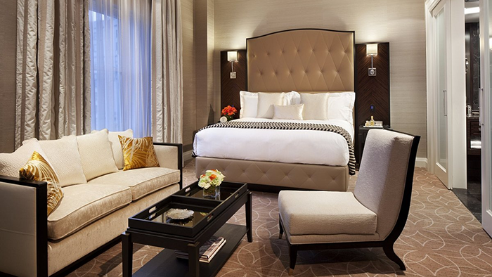 The inside of a guest suite at the Rosewood Hotel Georgia. Two gold and white pillows sit on a sofa on the left side of the room.