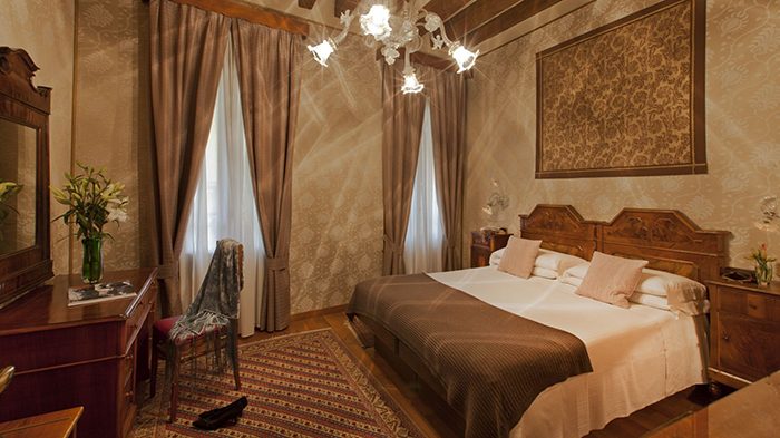 A guest room at the Hotel Saturnia & International Venezia. The room is decorated in almost entirely earth tones.