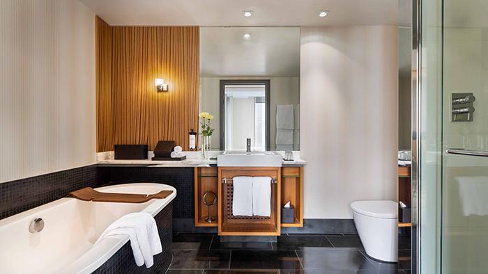 A guest bathroom at the Sofitel Auckland Viaduct Harbour Hotel. The wood accents add a pop of color to the mostly monochrome room.