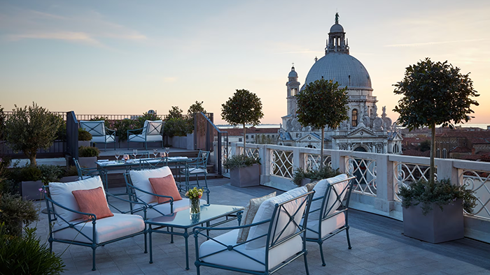 A balcony area at The St. Regis Venice photographed at dusk. It offers a lovely view of the Basilica Santa Maria della Salute just past the water.