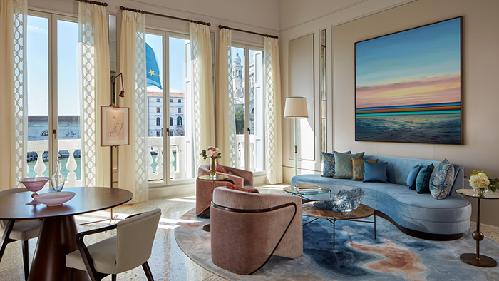 The inside of one of The St. Regis Venice's guest suites. A painting of a beach at sunset hangs above a large sofa.