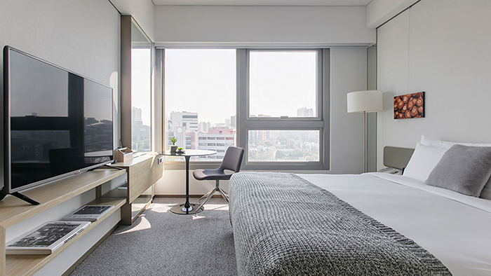 A guest room at the Hotel Stage. The Hong Kong cityscape is visible through the room's window.