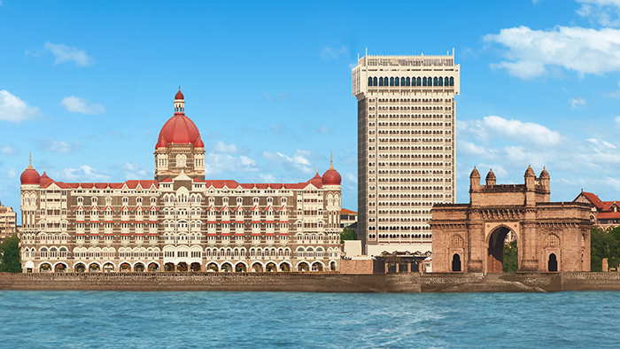 An exterior shot of The Taj Mahal Palace Hotel in Mumbai, India. The Gateway Of India Mumbai is visible to the right of the hotel.