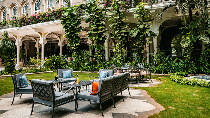 A courtyard inside the The Taj Mahal Palace, Mumbai. There's lots of seating and plenty of plant life.