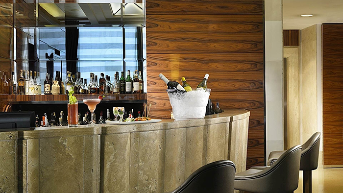 A bar at UNAHOTELS Dec Roma. Three bottles of what looks to be white wine are seen taking an ice bath.